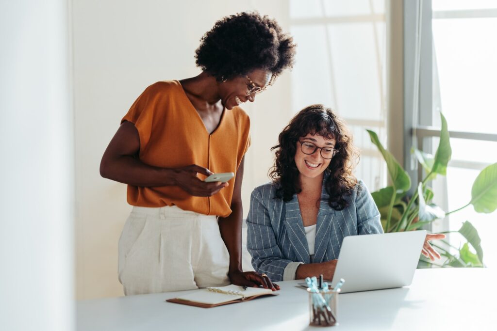 African american woman with caucasian woman at desk, both smiling