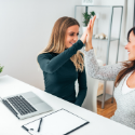 Two woman high-fiving in an office