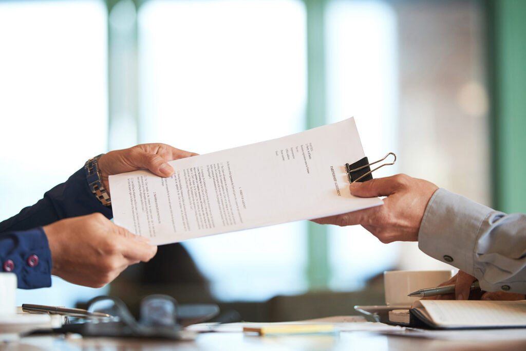 Man handing paperwork to woman with binder clip