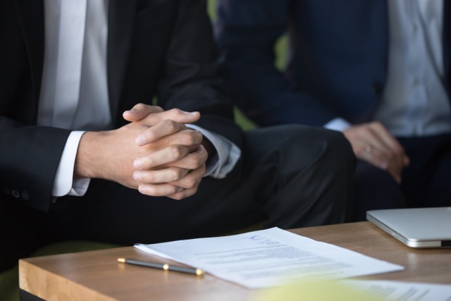 Male clasped hands clenched together, businessman at meeting negotiations or legal advice focused on listening or making decision, consulting about contract, consideration concept, close up view