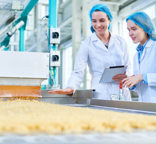 Food manufacturing employees wearing coats and hair nets