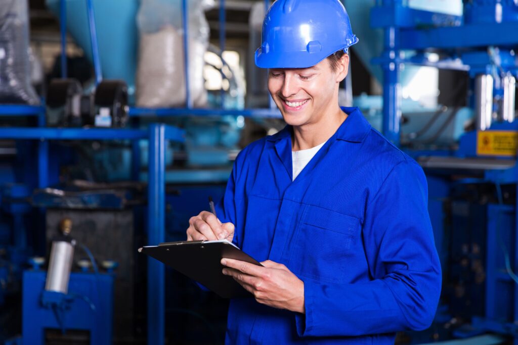 Man wearing bright blue safety gear like hard hat and uniform, holding clipboard smiling